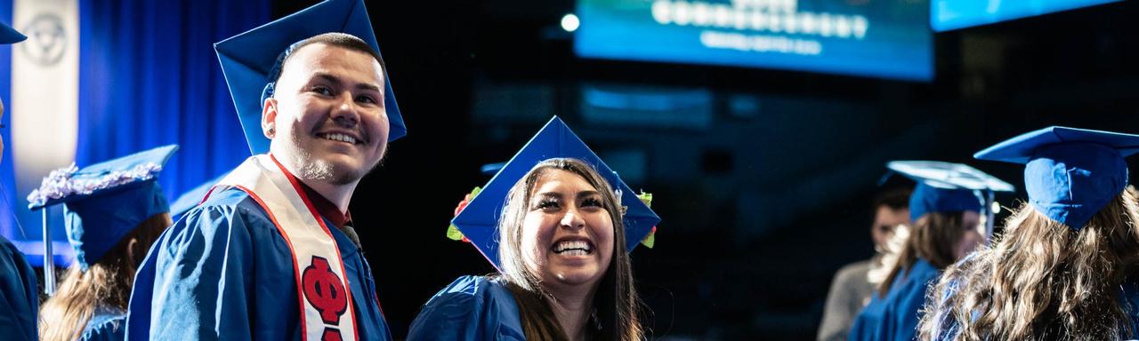 students standing at commencement in cap and gown